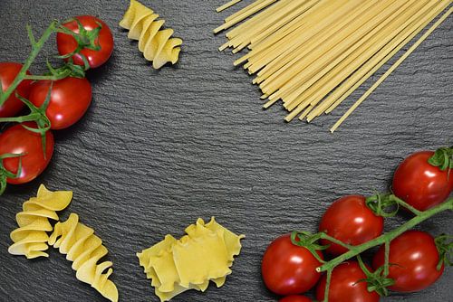Noodles and tomatoes against a dark background