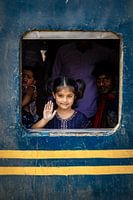 Une fille regarde par la fenêtre d'un train et fait un signe de la main