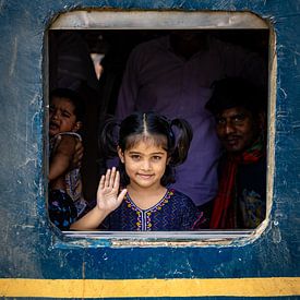 Girl looks out window of train and waves by Steven World Traveller