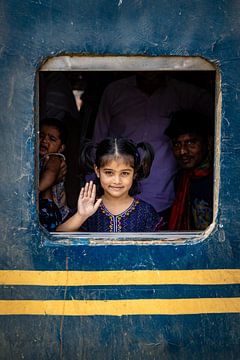Girl looks out window of train and waves by Steven World Traveller