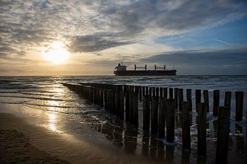 Le soleil couchant avec une bateau sur la plage Zoutelande Zeeland sur Alida Stam-Honders