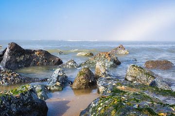 Strand mit Felsen und Nebelbogen