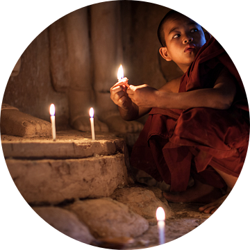 BAGHAN,MYANMAR, DECEMBER 12 2015 -Jonge  monnik steekt kaarsen aan bij beeld van Budha van Wout Kok
