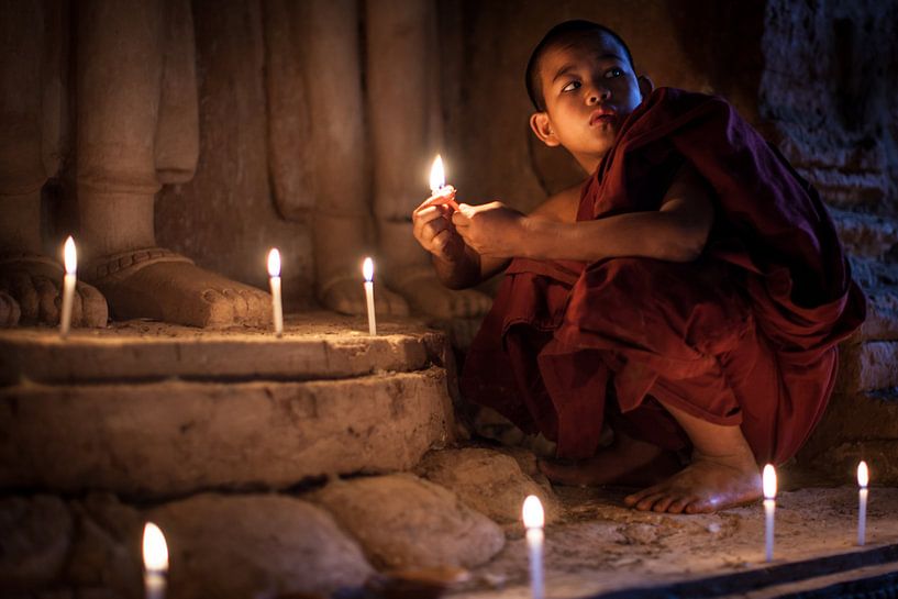 BAGHAN, MYANMAR, 12 DÉCEMBRE 2015 - Un jeune moine allume des bougies devant la statue de Budha. par Wout Kok