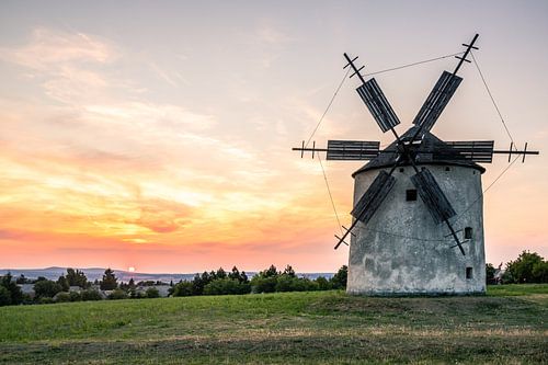 Oude windmolen van steen en hout in de zonsondergang
