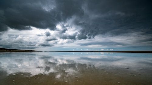 Stormy skies with reflections on the sand