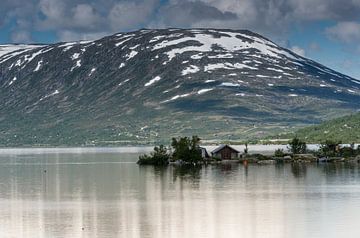 vieille maison au bord d'un fjord avec les montagnes enneigées en été en arrière-plan