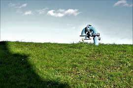 Des tuyaux industriels bleus dans l'herbe avec un ciel nuageux sur Maud De Vries