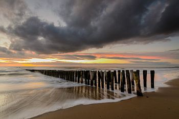 Paalhoofden op het strand na zonsondergang