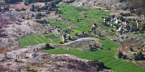 Een klein huisje met een rood dak tussen de smaragdgroene alpenweiden en stenen ver beneden, een sym