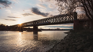 Eisenbahnbrücke mit Blick auf Mainz mit Sonnenstern am Rhein