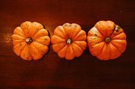 drie oranje pompoenen op een rij op tafel van Margriet Hulsker thumbnail