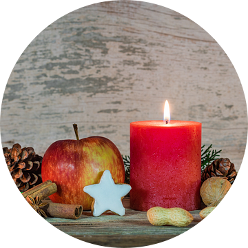 Kerstmis rode kaars vlam met rode appel, ster koekje en noten decoratie met houten achtergrond van Alex Winter