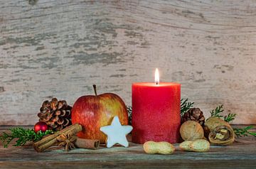 Kerstmis rode kaars vlam met rode appel, ster koekje en noten decoratie met houten achtergrond