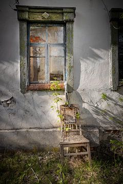 chaise devant la fenêtre d'une maison abandonnée