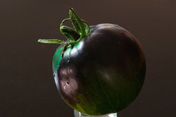 Kunst met groenten en regendruppels van een zwarte tomaat