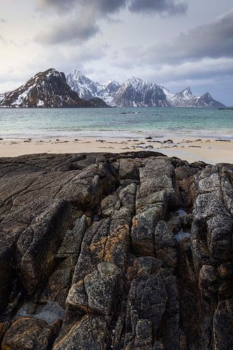 Het majestueuze Hauklandstrand op de Lofoten, met ruige rotsen en besneeuwde...