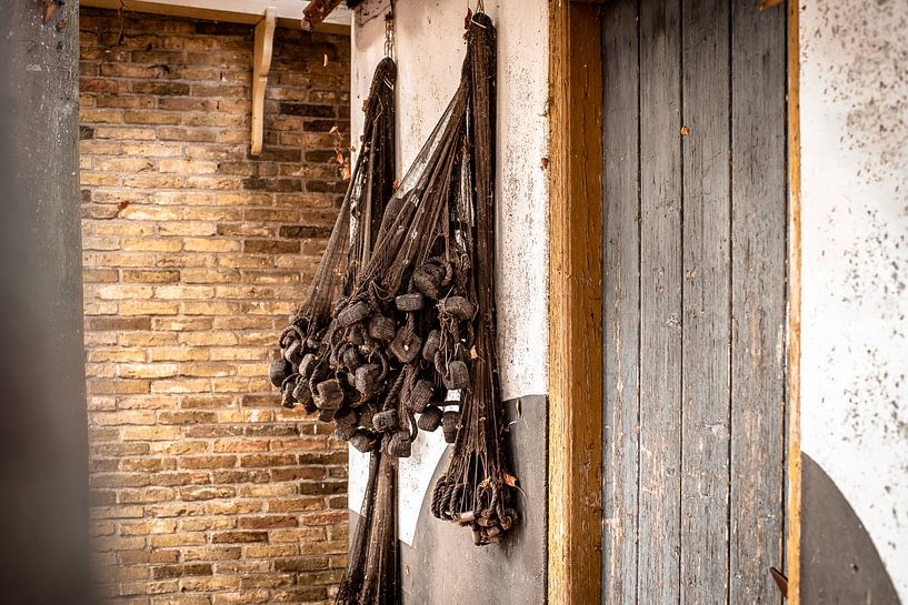 Trocknende Retro- Fischernetze an der Wand des Hauses des alten Fischers von Fotografiecor .nl
