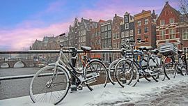 Stadsgezicht van besneeuwd Amsterdm in de winter in Nederland bij zonsondergang van Eye on You
