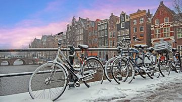 Stadsgezicht van besneeuwd Amsterdm in de winter in Nederland bij zonsondergang van Eye on You
