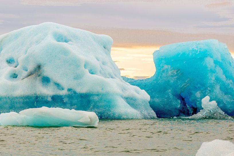 Big ice floes in Jökulsárlón ice lake in Iceland with deep blue color against an orange sky by Hein Fleuren