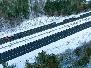 Autobahn durch eine verschneite Waldlandschaft von oben gesehen