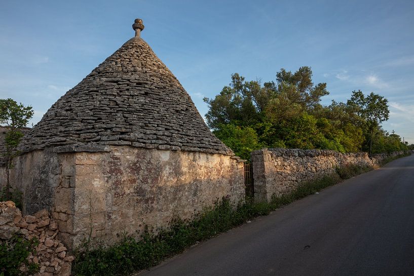 Trullo (maison en pierre) le long d'une route dans la lumière du soir, sud de l'Italie par Joost Adriaanse
