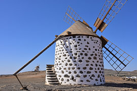 A windmill in the barren landscape of Fuerteventura by Tomherkules