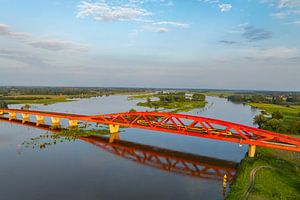 Eisenbahnbrücke in einem farbenfrohen Sonnenuntergang über die IJssel