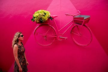 Meisje met fiets in een roze omgeving van Reis Genie
