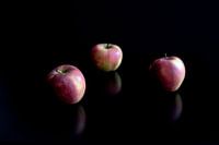 Des pommes se reflètent sur une table noire