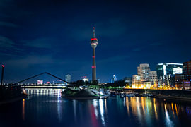Medienhafen Düsseldorf bei Nacht mit Gehry-Bauten, Rheinturm und beleuchtetem Hafenbecken / Marina von Your Happy Life
