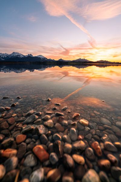 Reflection with shore stones of the sunset at the Hopfensee in the Allgäu region by Leo Schindzielorz