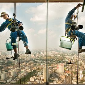 Fensterputzer hängen bei ihrer Arbeit in der Höhe von einem Wolkenkratzer von Nic Limper