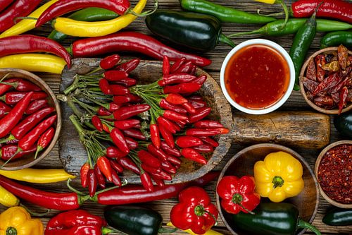 Kleurrijke variëteit van chilipepers en paprika's op rustiek hout