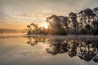 Zonsopgang op een meer met een schiereiland en stijgende mist
