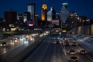 Die Skyline von Minneapolis am Abend, gesehen von der Brücke mit der Autobahn und den Autolichtern