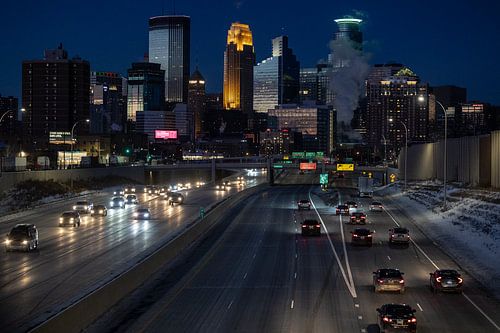 Minneapolis Skyline in de avond, gezien van de brug met de snelweg en autolichten