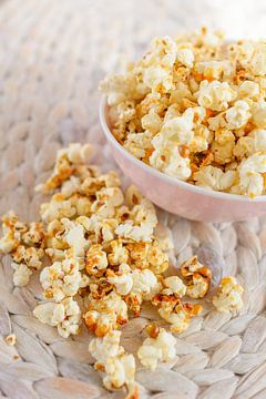 Fresh made popcorn lies in a cup on a table.