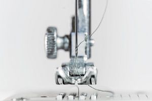 Nadel und Nähfuß einer Nähmaschine als extreme Makroaufnahme, technische Erfindung für die Bekleidun von Maren Winter