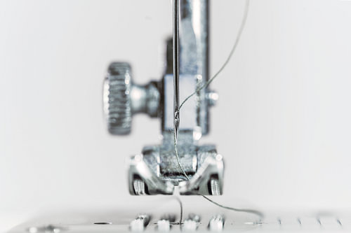 Nadel und Nähfuß einer Nähmaschine als extreme Makroaufnahme, technische Erfindung für die Bekleidun