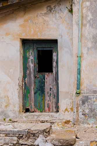 Bâtiment abandonné avec une porte vert turquoise et une gouttière