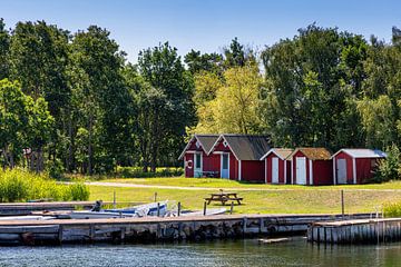 Red boathouses on Sweden's Baltic coast by Adelheid Smitt