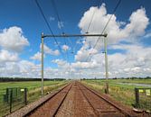 Bahnübergang mit unbegrenzter Schiene zum Horizont mit hellem blauem Himmel und weißen Wolken von André Muller Miniaturansicht