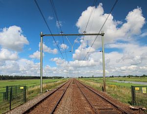 Bahnübergang mit unbegrenzter Schiene zum Horizont mit hellem blauem Himmel und weißen Wolken