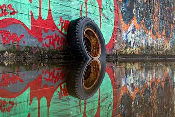 Tyre with a rim reflected in the water. by Lex van der Putten