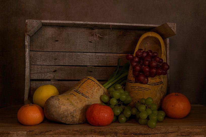still life with a wooden box with old dutch worn out wooden shoes and various fruits by ChrisWillemsen
