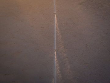 Minimalistisches Foto von fahrenden Autos in der Morgensonne in der Sossusvlei-Wüste | Reisefotograf von Teun Janssen