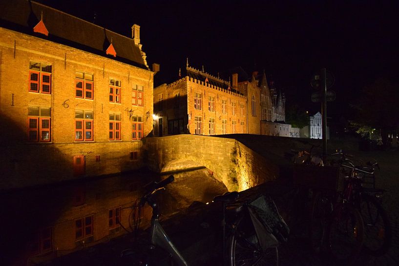 Vue nocturne de Bruges avec un vélo devant un pont illuminé par Studio LE-gals