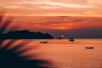 Varende boten in Thailand tijdens zonsondergang in de zee van Madinja Groenenberg